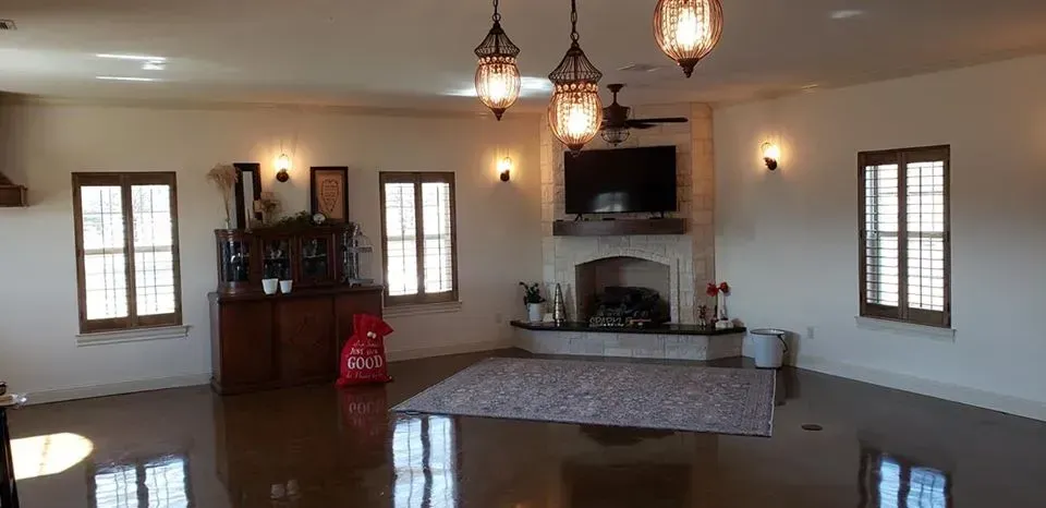 Spacious living room with hanging lanterns, large windows, and a patterned sofa centered on the polished floor