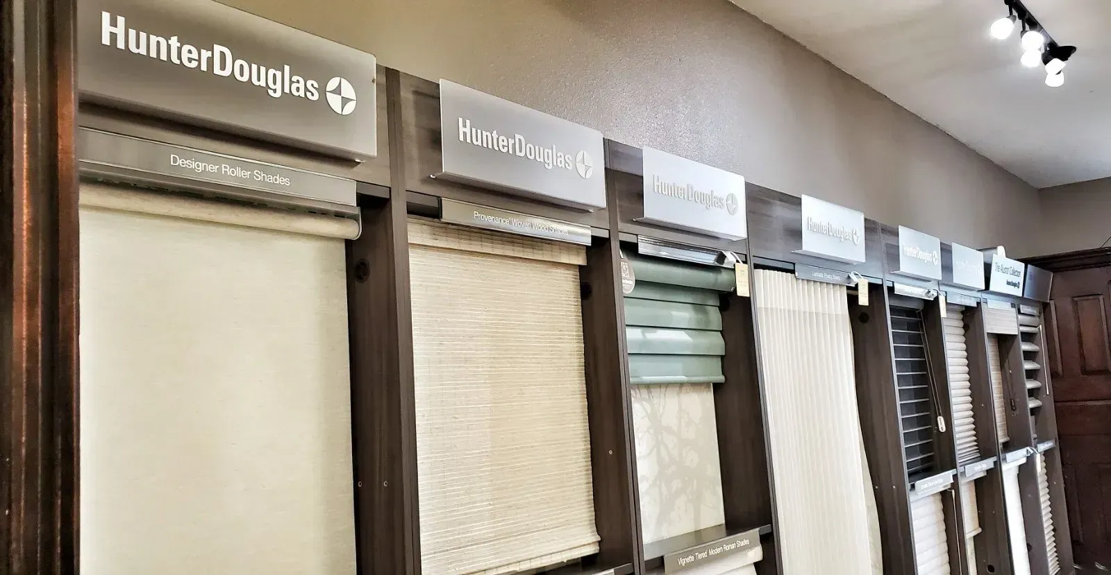 Hunter Douglas window blinds display with multiple beige and gray shades in a showroom