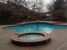 A large swimming pool with a hot tub in the middle of it.
