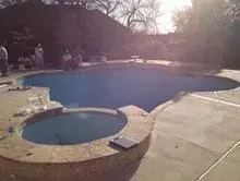 A large swimming pool with a hot tub in the middle of it.