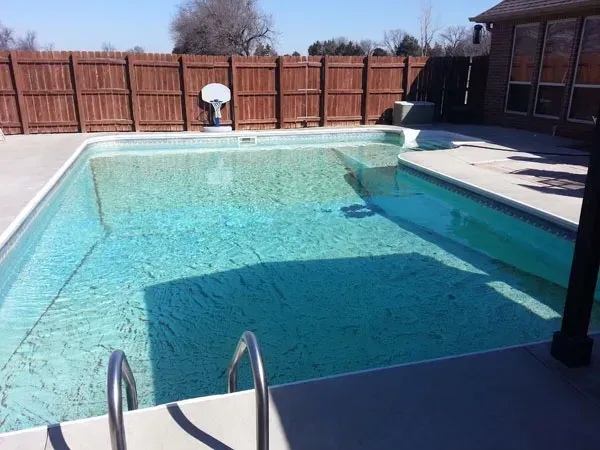 A large swimming pool with a wooden fence surrounding it