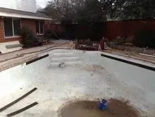 A swimming pool is being remodeled in the backyard of a house.