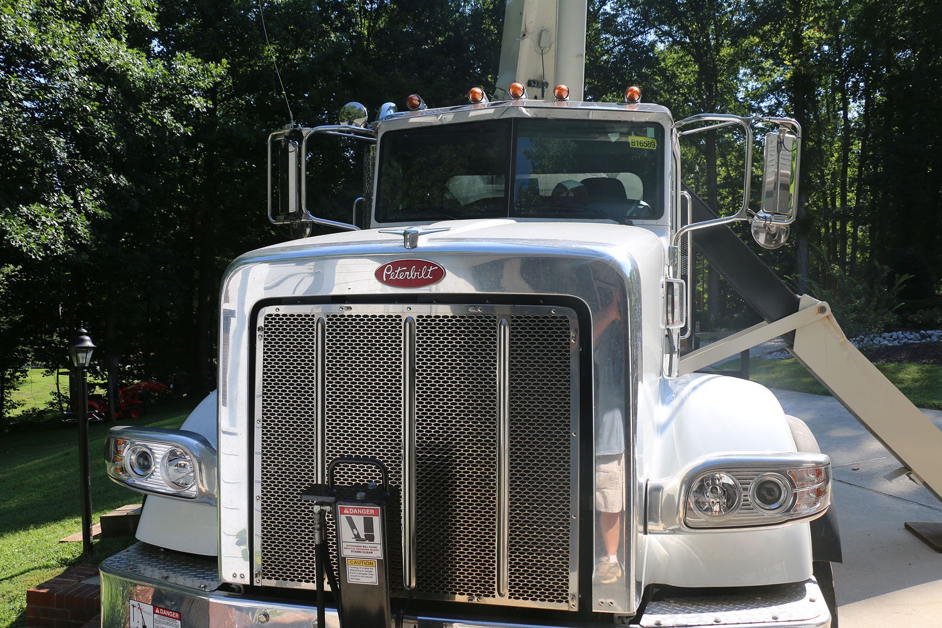 Front view of a white semi-truck with chrome grille parked outdoors in sunlight