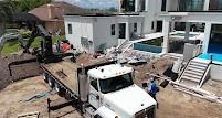 Construction site with a white truck, excavator, and partially built house.