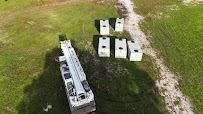 Aerial view: Truck with crane next to several white rectangular structures on grassy field.