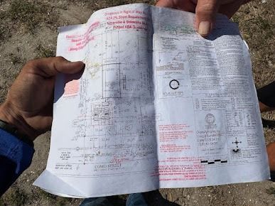 Hands holding a detailed map outdoors. The map has annotations in red ink.