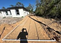 A septic system drain field under construction near a white house.