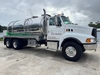 White septic tank truck on a concrete surface against a cloudy sky.