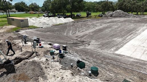 Construction site with workers, equipment, and piles of sand.