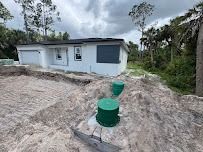 White house with green septic tanks in front, construction site setting.
