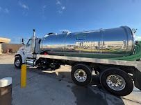 A shiny silver septic tank truck parked outside on a sunny day.