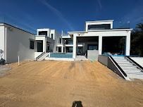 Modern white house with a pool and construction site in the foreground under a blue sky.
