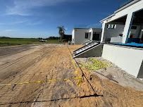 Construction site with sandy ground, a partially built white building, and yellow caution tape.