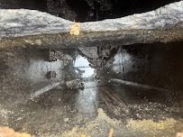 Inside view of a dark rectangular vent, showing the opening and surrounding dirt and debris.