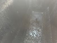 Inside a dark, narrow chimney or flue. Debris covers the bottom, leading to a small square opening.