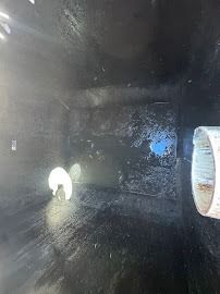 Inside view of a dark, rectangular tank. A white pipe and two circular openings are visible on the sides.