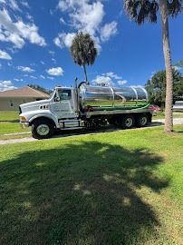 White septic tank truck parked on grass, sunny day.