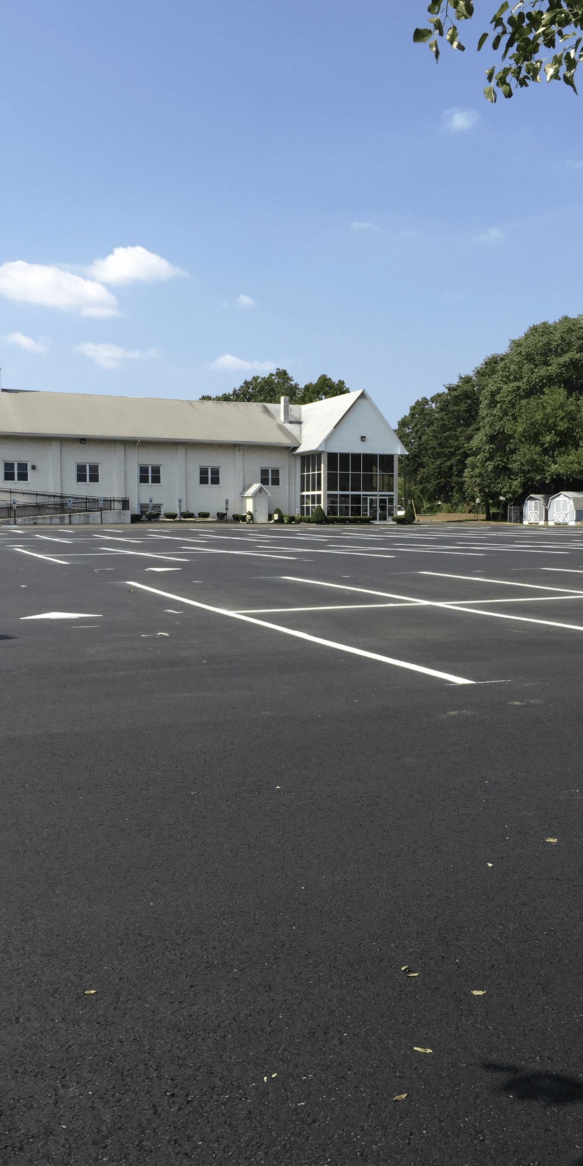 A white building with a spacious parking lot in front of it