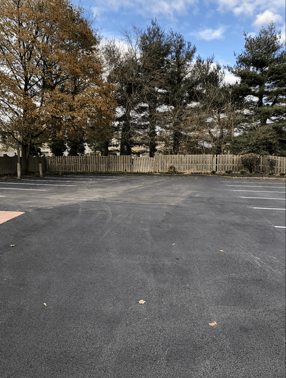 A parking lot with a fence and trees in the background