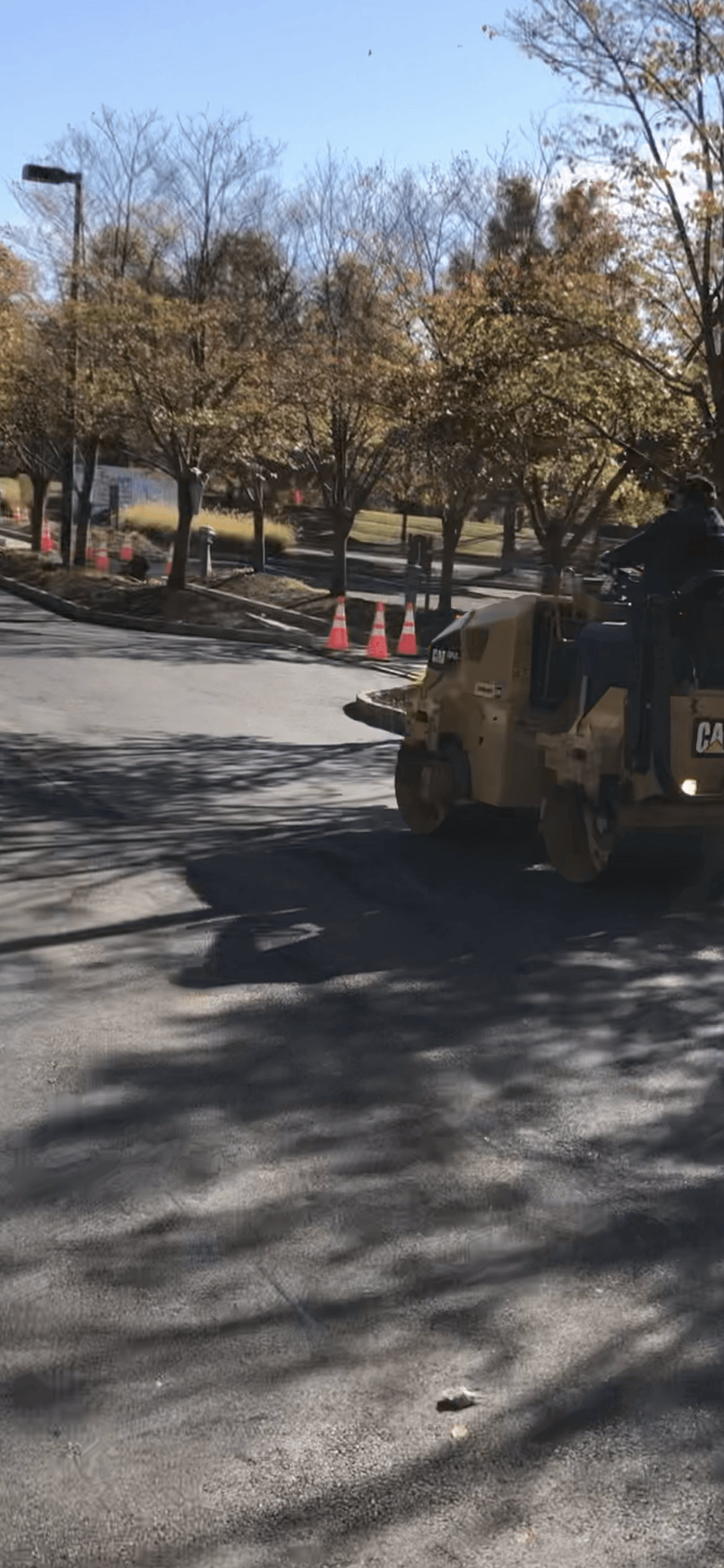 A man is driving an asphalt roller down a street