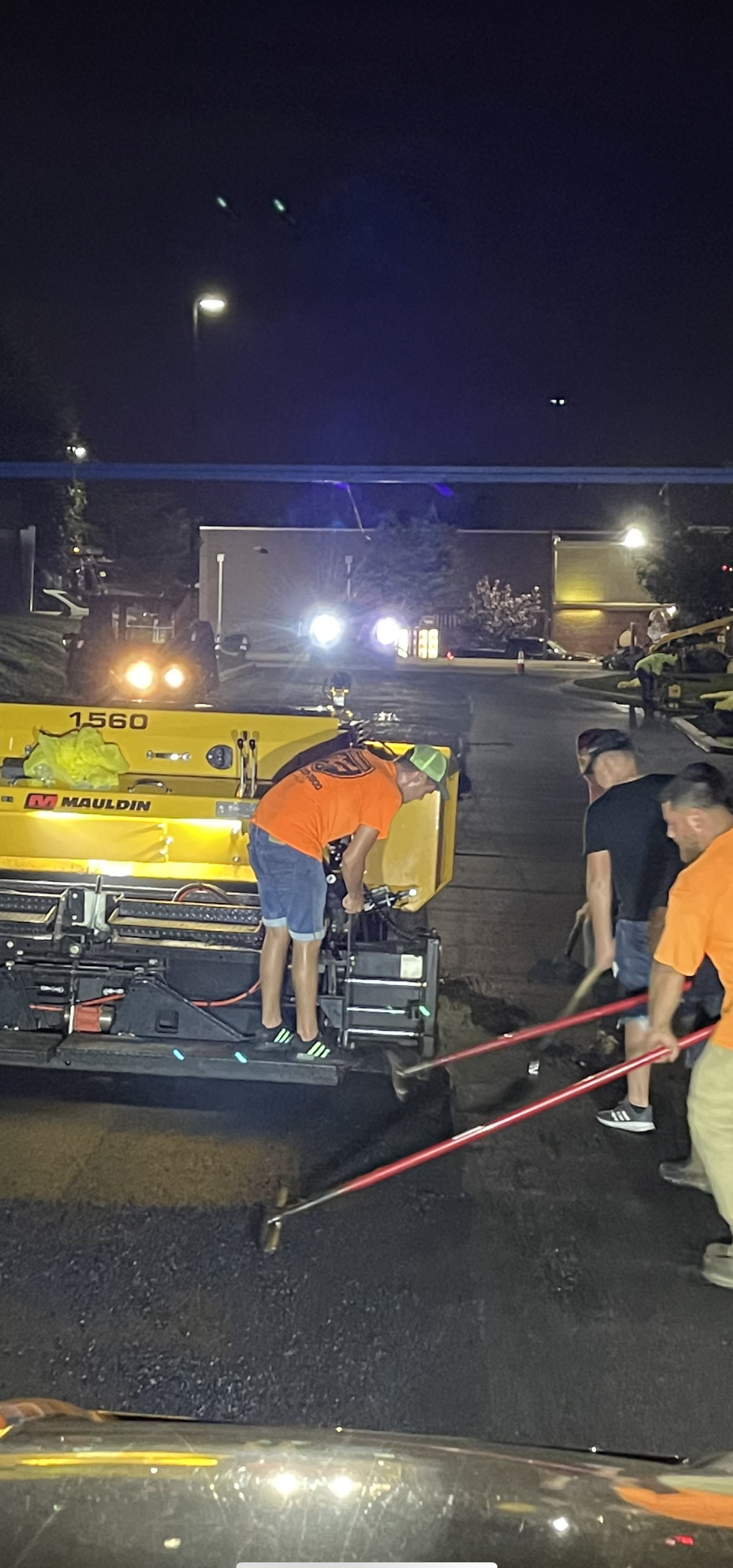 A group of people are working on a road at night