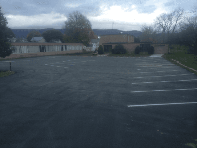 A parking lot with a building in the background on a cloudy day