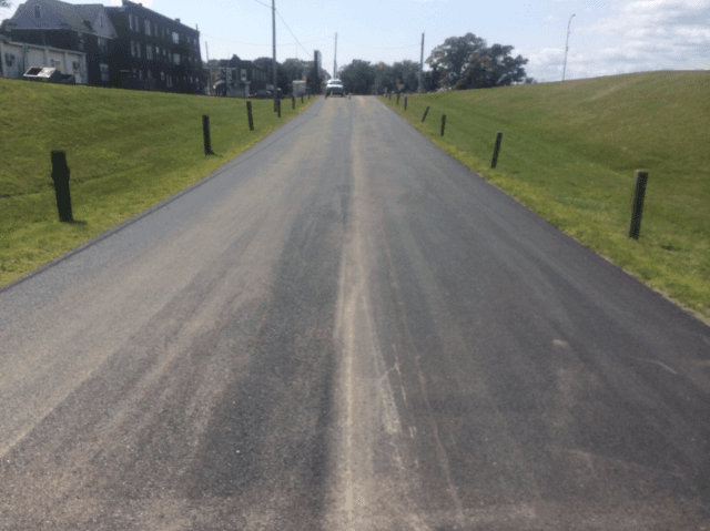 A road with a grassy hill on the side of it