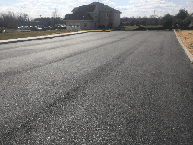 A residential street with a house in the background