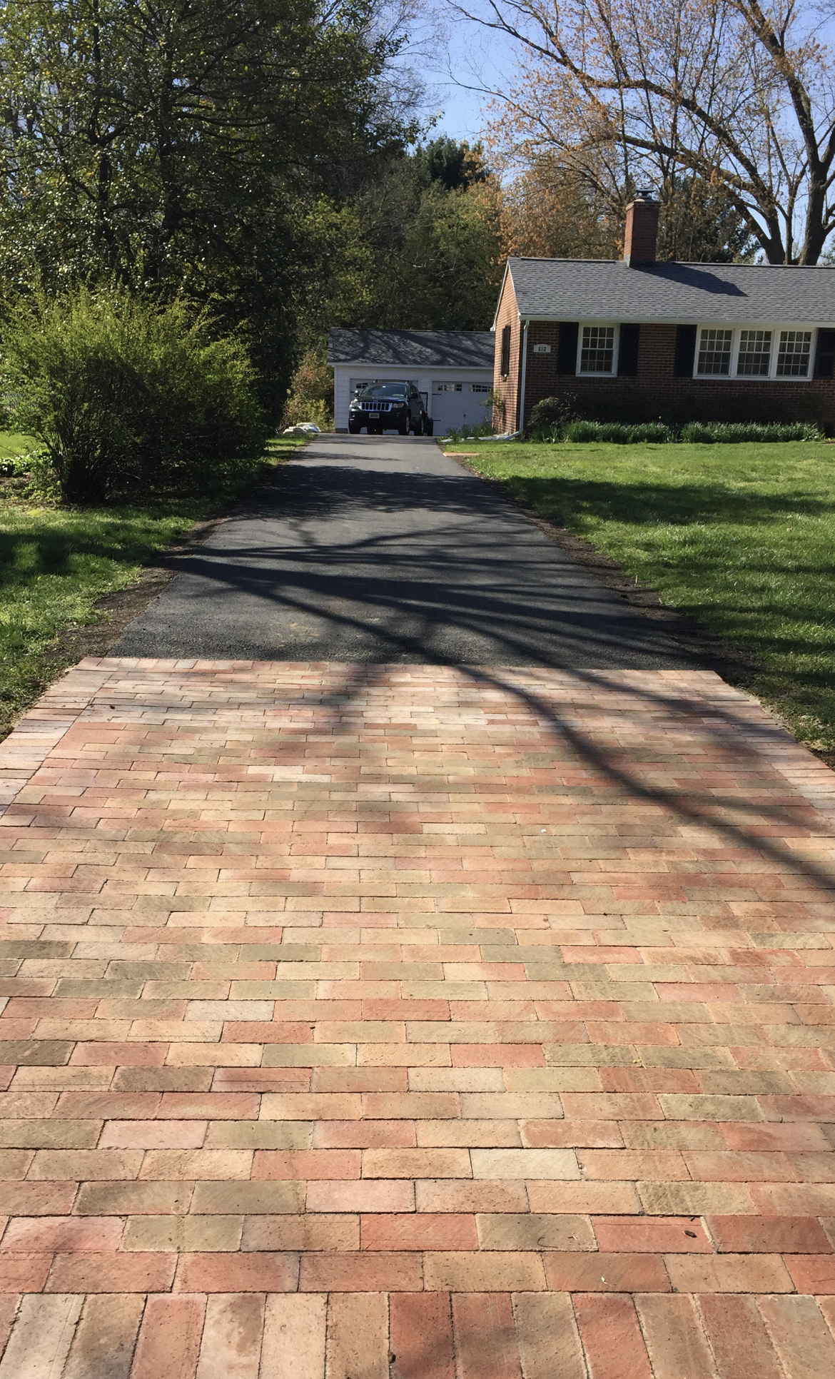 A brick driveway leading to a house with a car parked in the driveway
