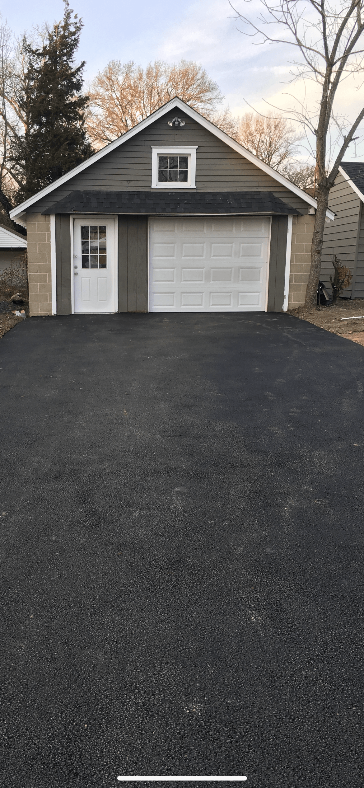 A garage with a driveway leading to it and a house in the background