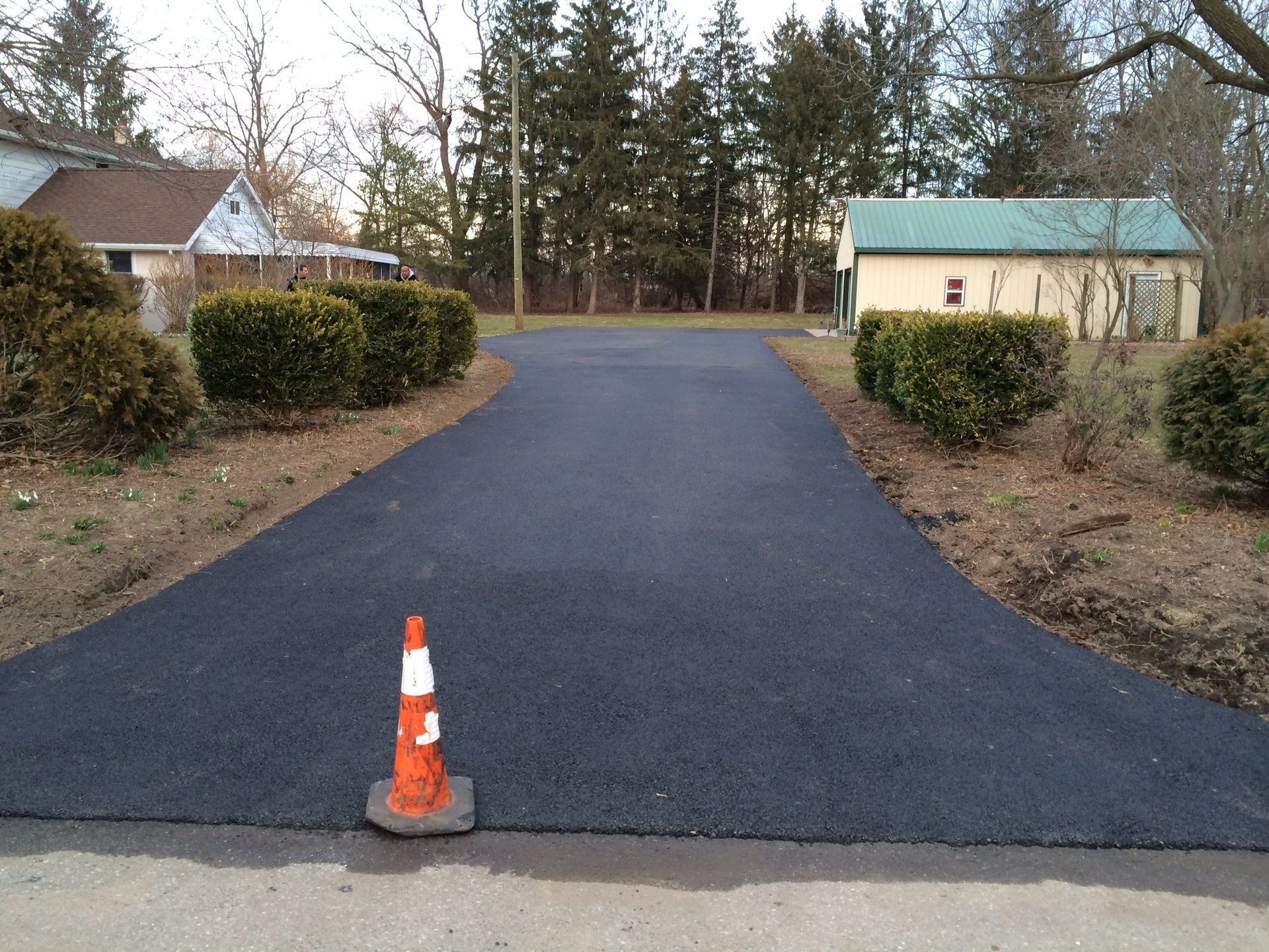 An orange and white traffic cone is on the side of a road