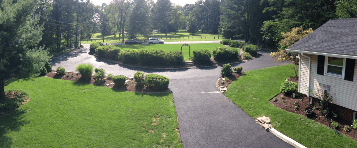 An aerial view of a driveway leading to a house surrounded by trees