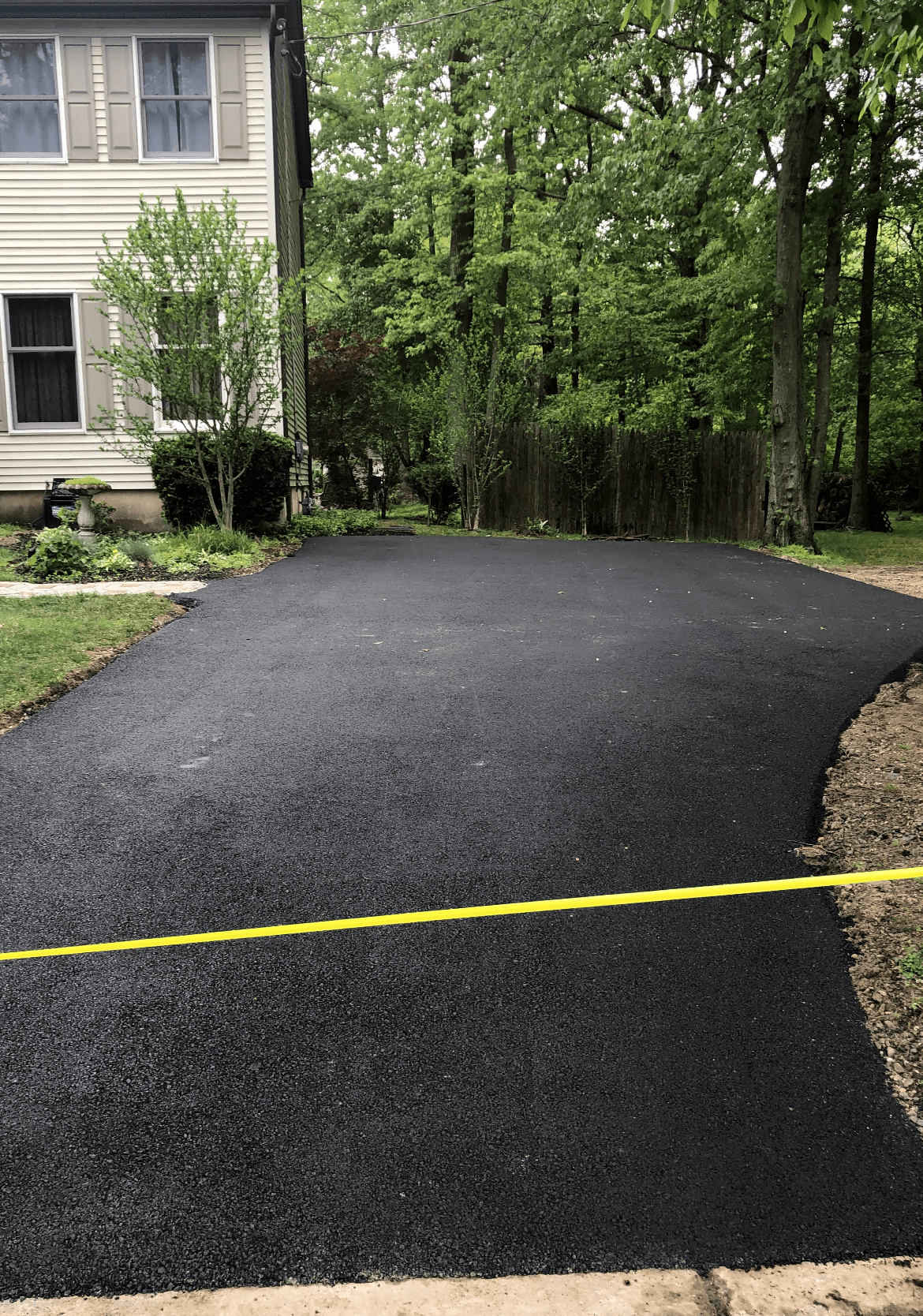 An asphalt driveway is being built in front of a house