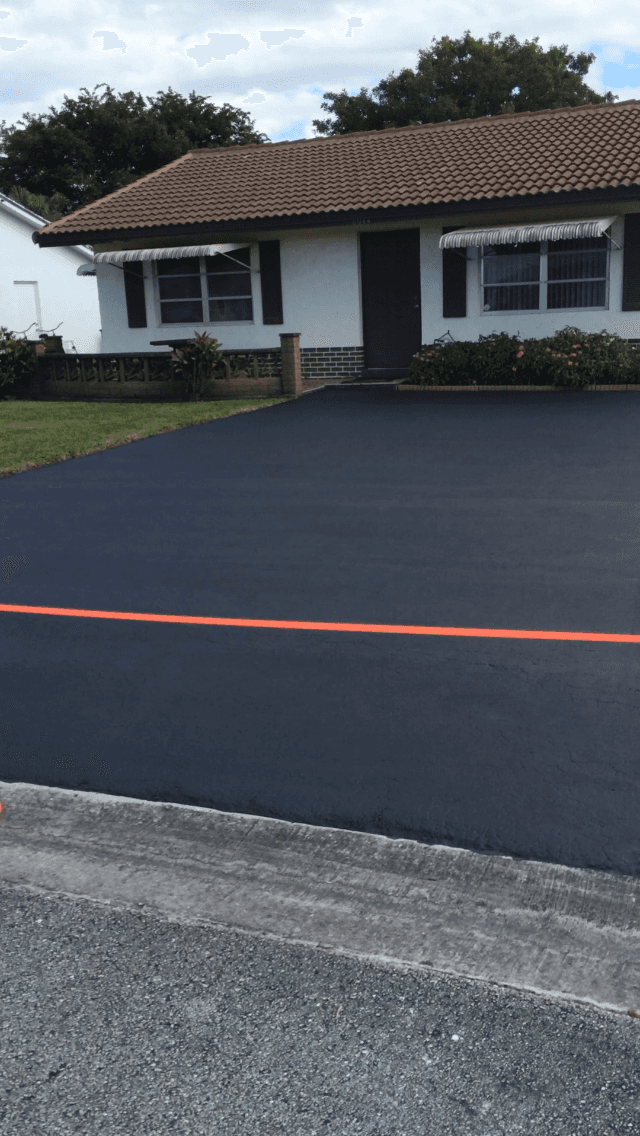 A house with a black asphalt driveway in front of it