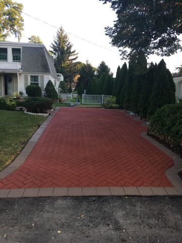 A red brick driveway leading to a white house