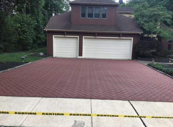 A brick driveway in front of a house with two garage doors