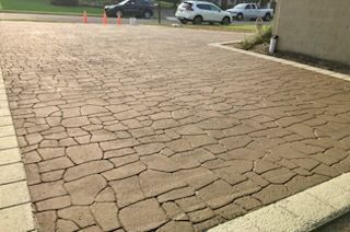 A brick driveway with cars parked on the side of it.