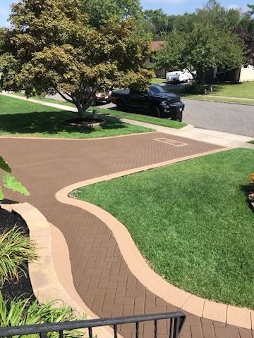 A car is parked in the driveway of a house next to a tree.