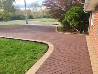 A red brick walkway leading to a brick house.