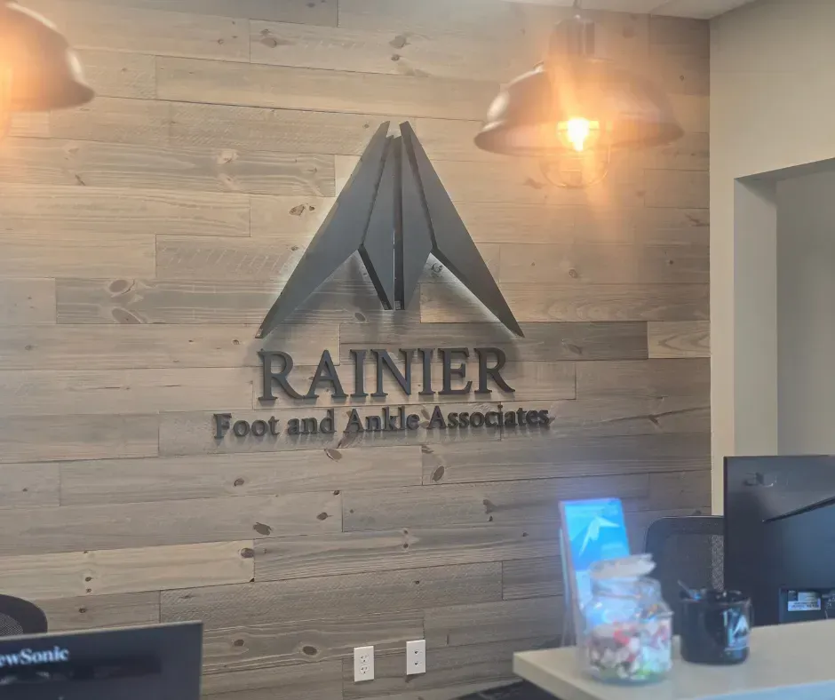 Logo for Rainier Foot and Ankle Associates above a reception desk on a wood-paneled wall.