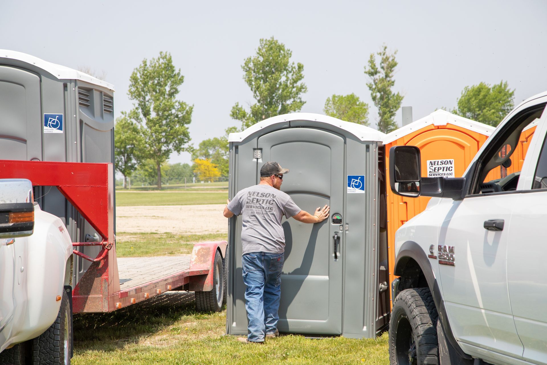 A man is standing in front of a portable toilet