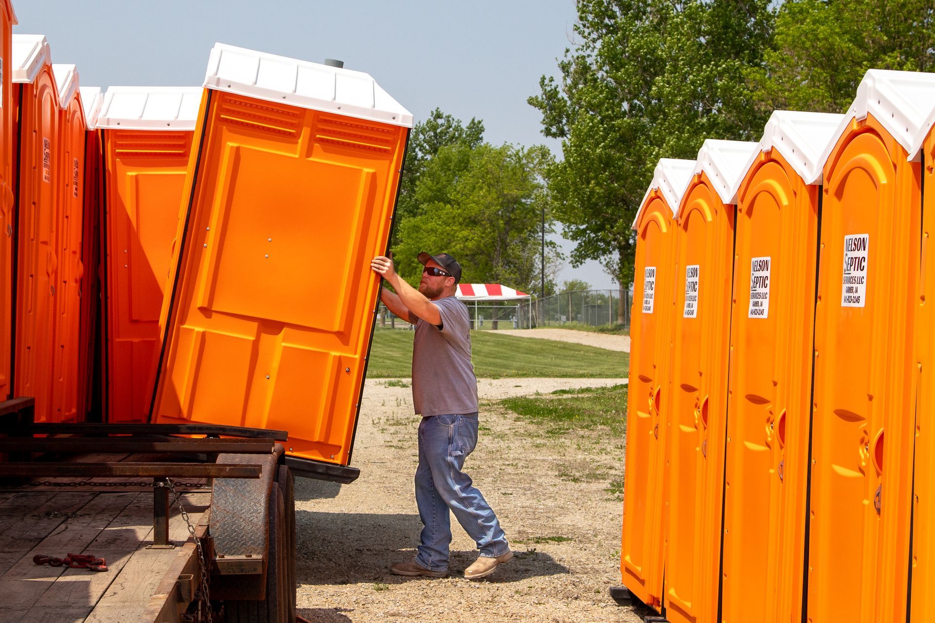 A man is loading portable toilets onto a trailer