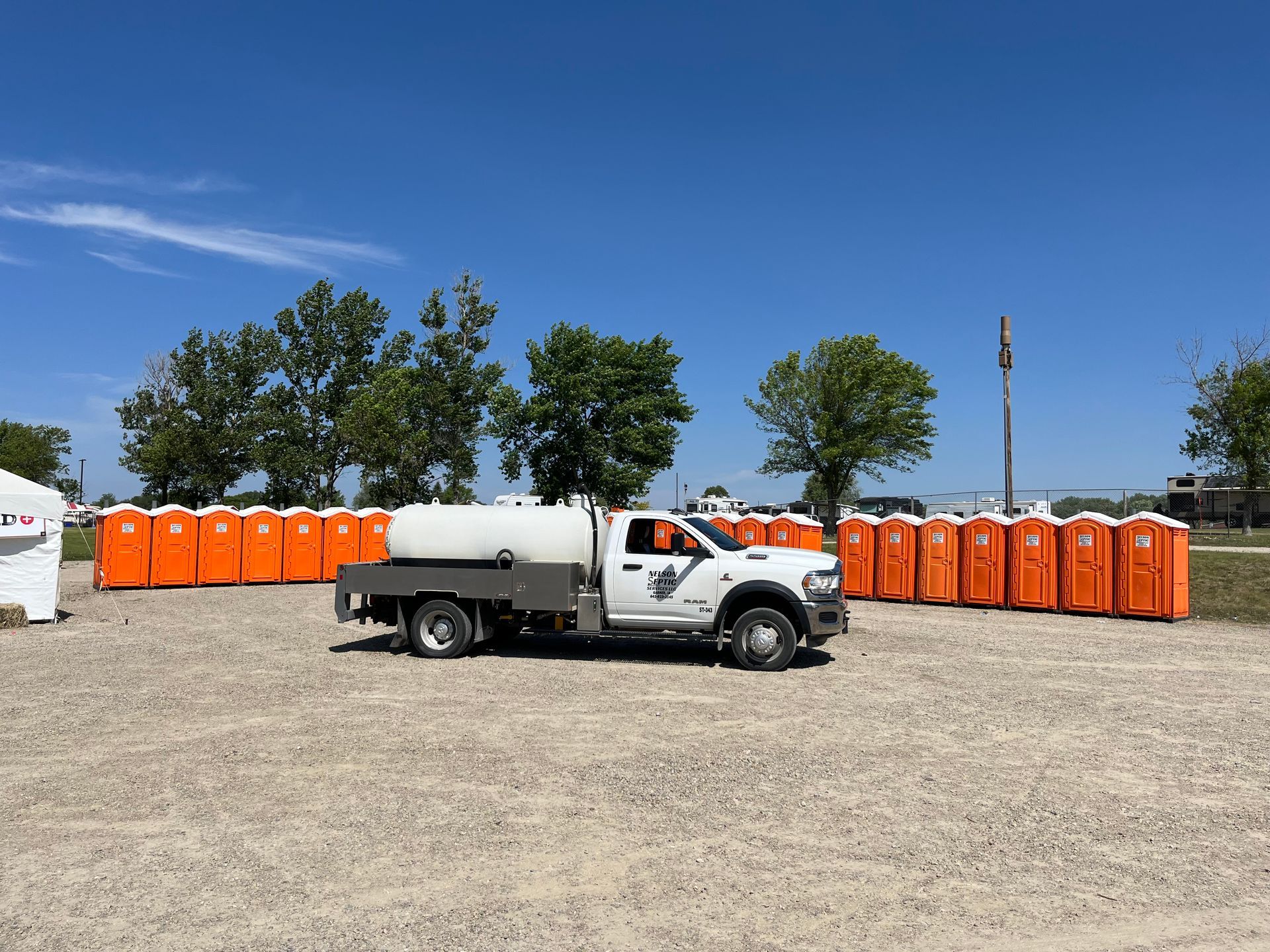 A white truck is parked in front of a row of orange portable toilets