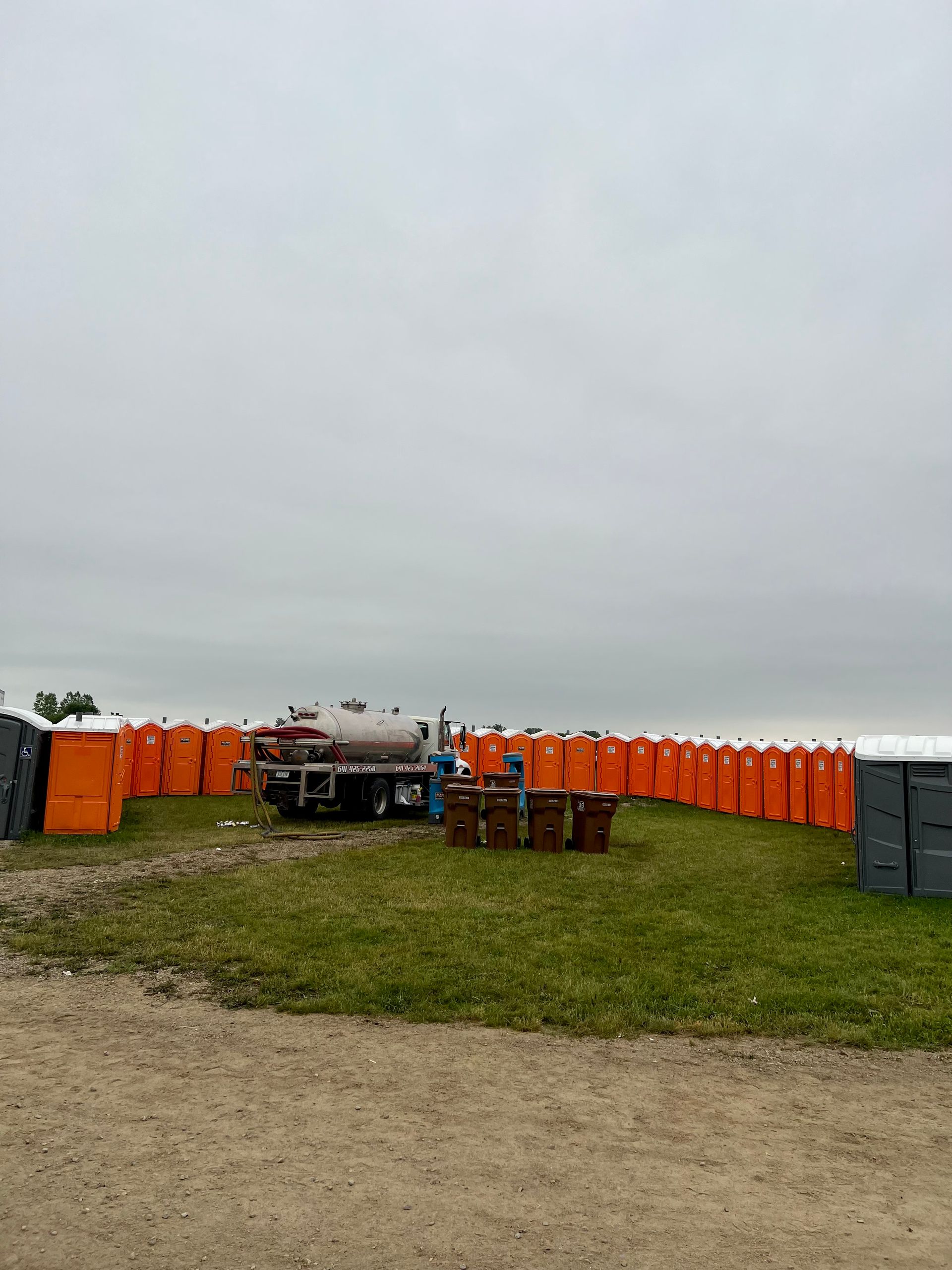 A row of portable toilets are lined up in a field