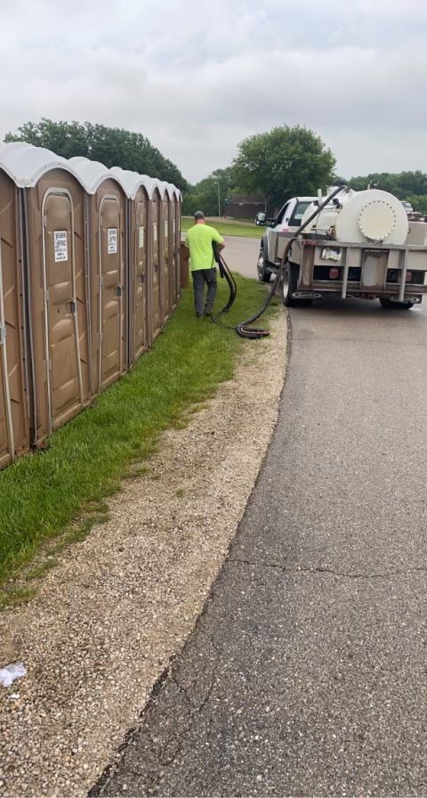 A man is standing next to a row of portable toilets