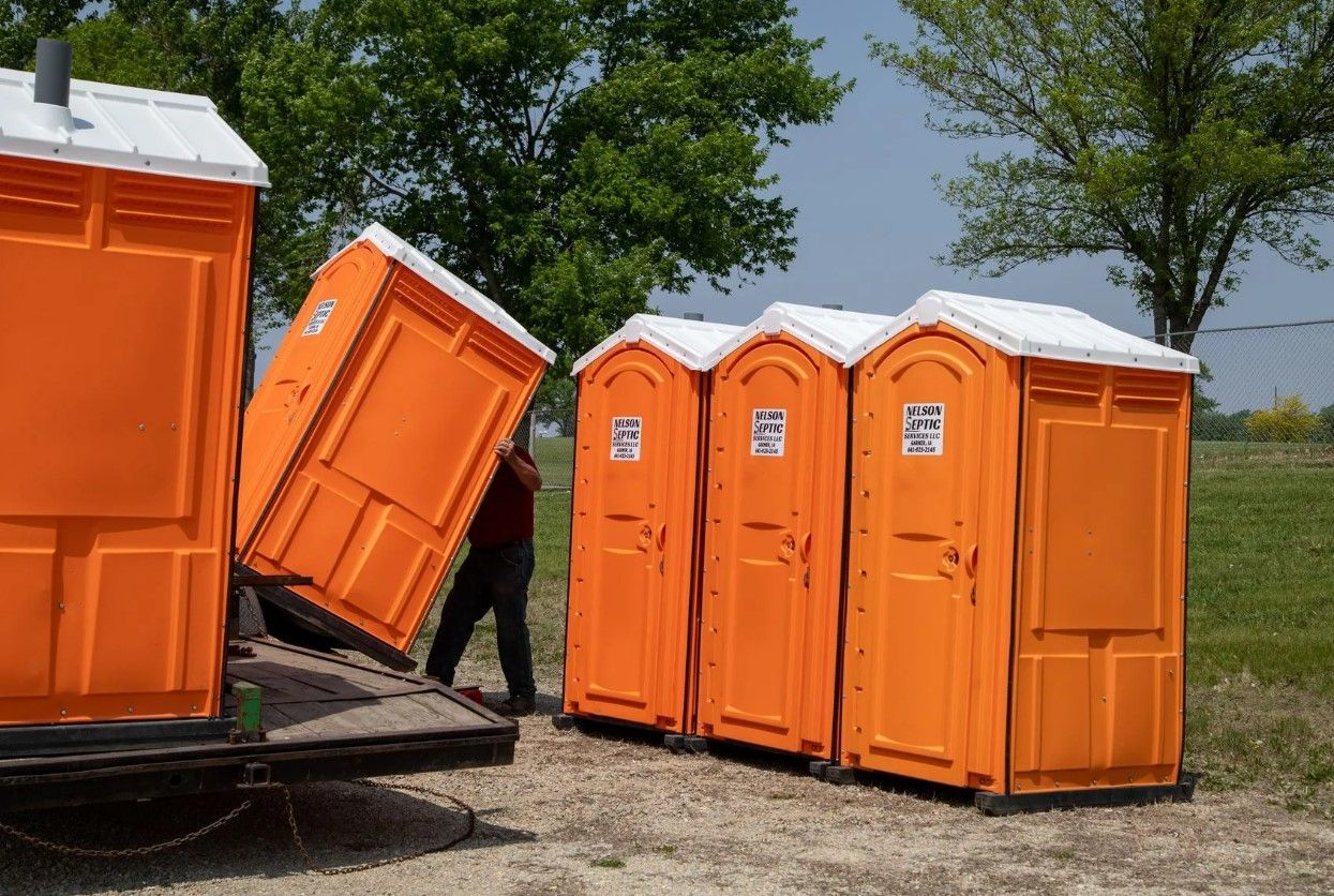 A man is loading portable toilets into a truck
