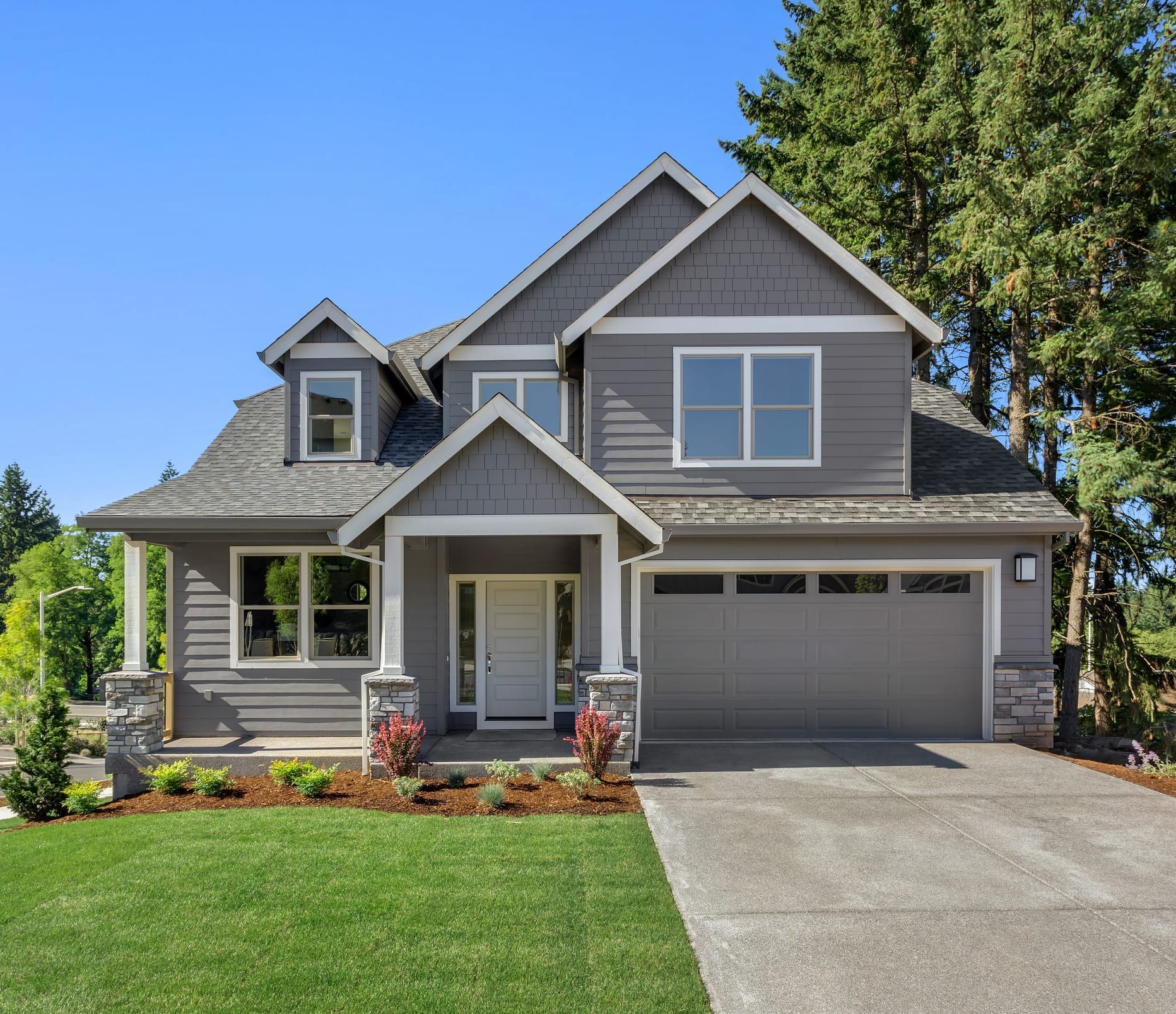 A large gray house with a garage and a driveway.
