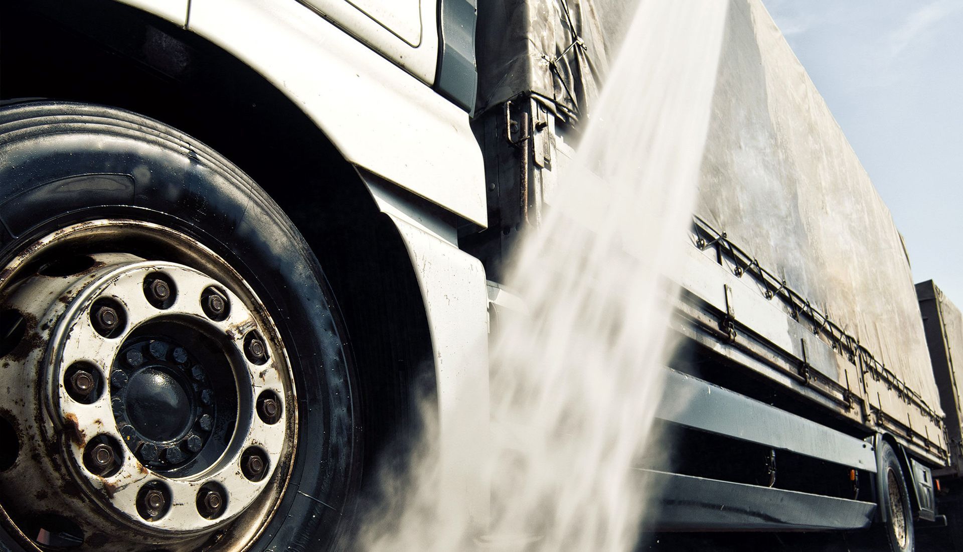 Close-up of a truck tire with water spraying from the wheel on a wet road