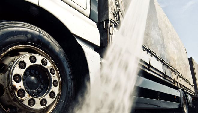 Close-up of a truck tire with water spraying from the wheel on a wet road