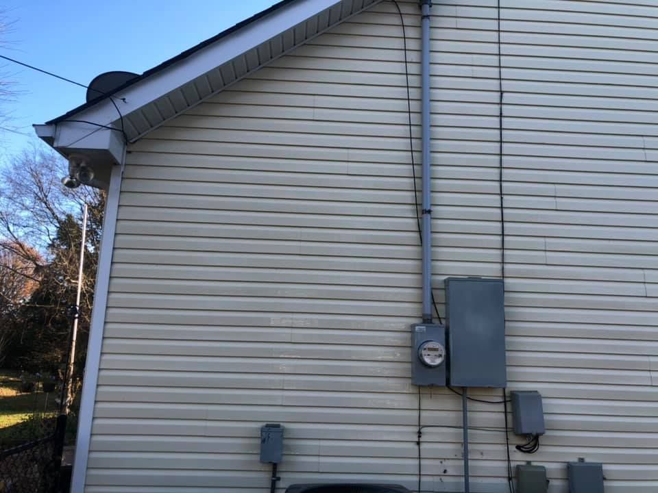 Side of a beige house with utility meters and electrical boxes mounted on the exterior wall.